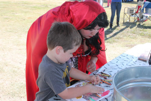 Walker colors a photo at the library booth's table alongside Little Red Riding Hood, Ann Marie Anderson.