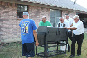Lenny Lewis gets help moving the cooker into place from members of the Collin County Sheriff’s Office Citizens on Patrol, Pete McCartney, Andy Barnes and Greg Griser, who is also a neighbor in Settler’s Creek.