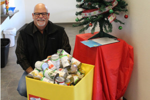 Princeton Mayor John-Mark Caldwell shows up off a box of can goods collected for the Battle of the Bridge Canned Food Drive this holiday season. Princeton and Farmersville are battling to see who can collect the most canned goods.