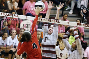 Shelbi Cook goes up for a block at the net as Sydney Bazan assists on the play